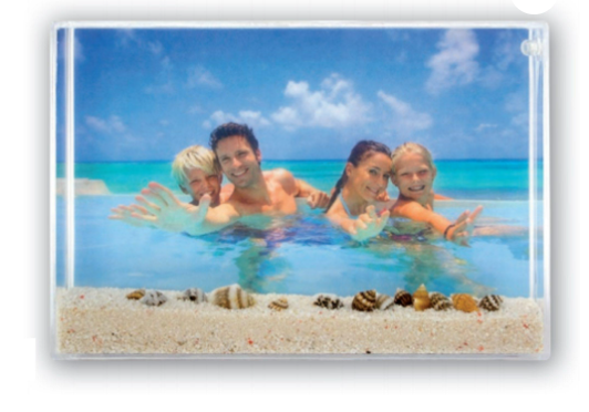 A clear sand frame with sand and shells and a family photo inside